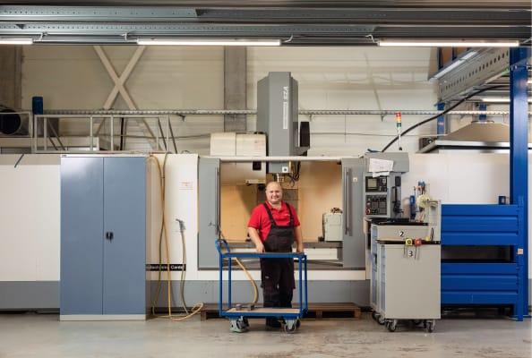 Engineer is standing next tu a CNC milling machine